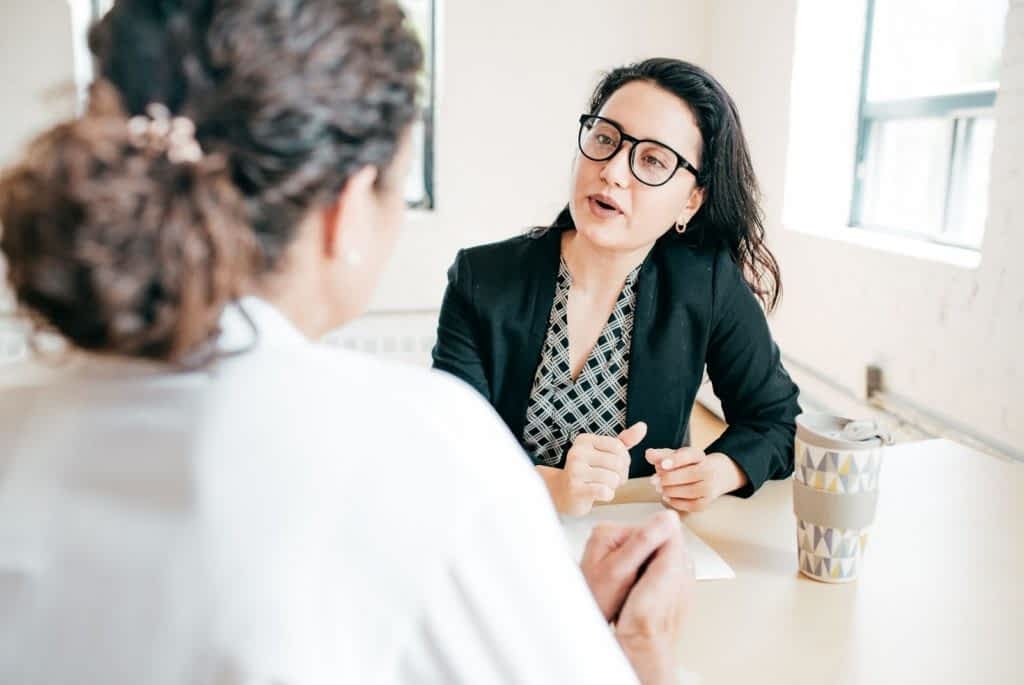 Two-women-having-a-discussion-at-desk